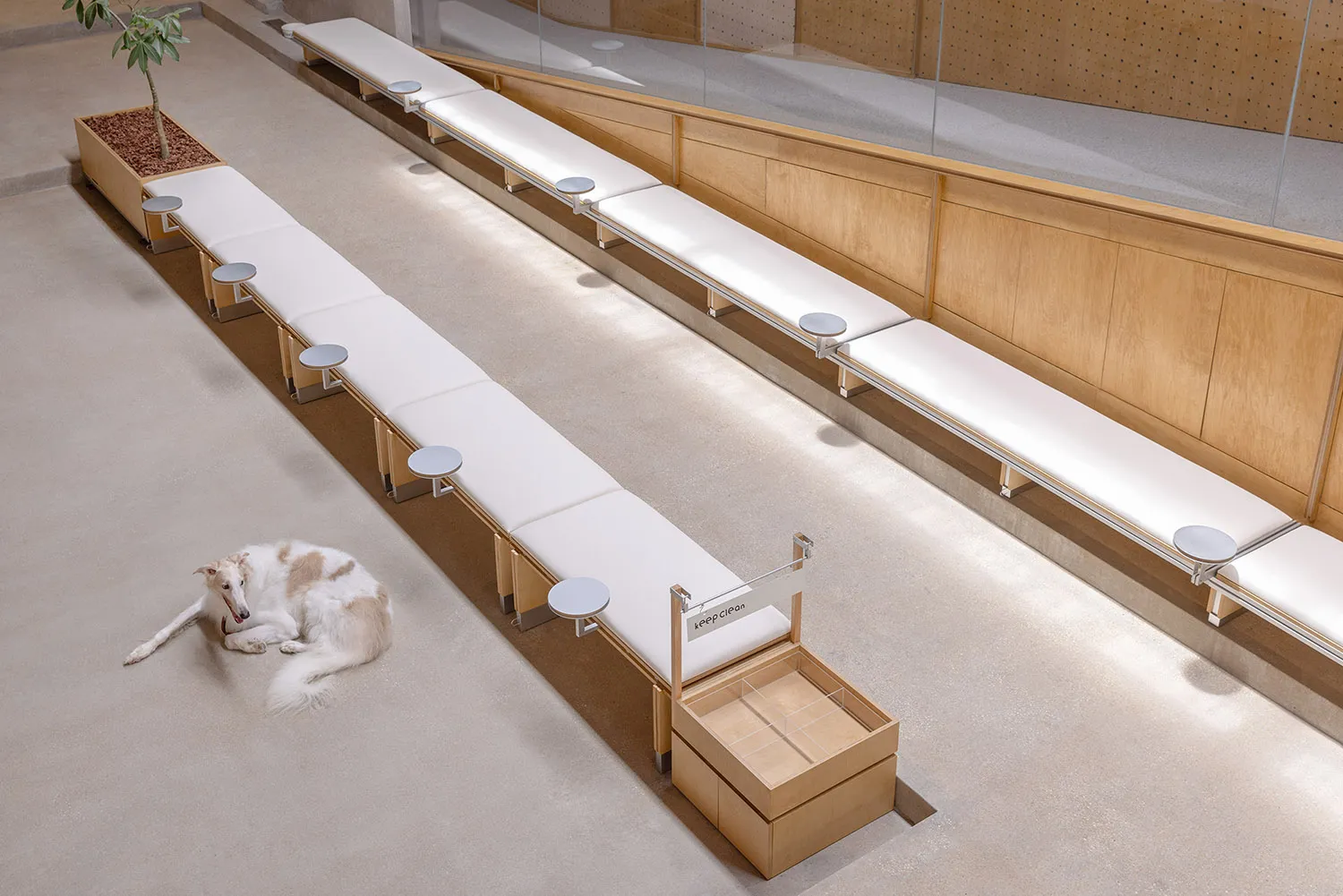 A spacious, industrial-style public area with long benches made of wood and covered in fabric.