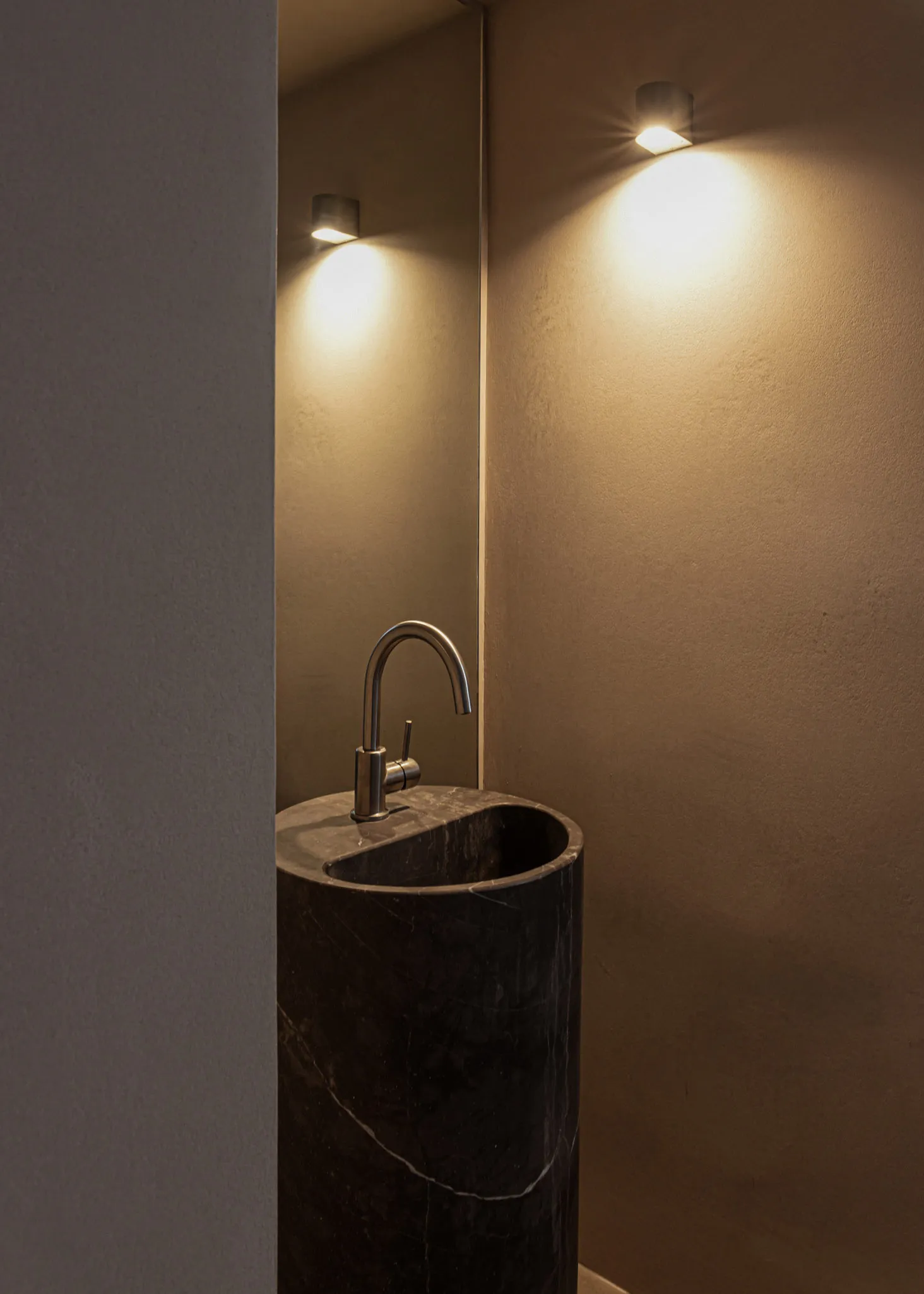 Modern minimalist bathroom with a sleek, black marble sink and metallic fixtures.