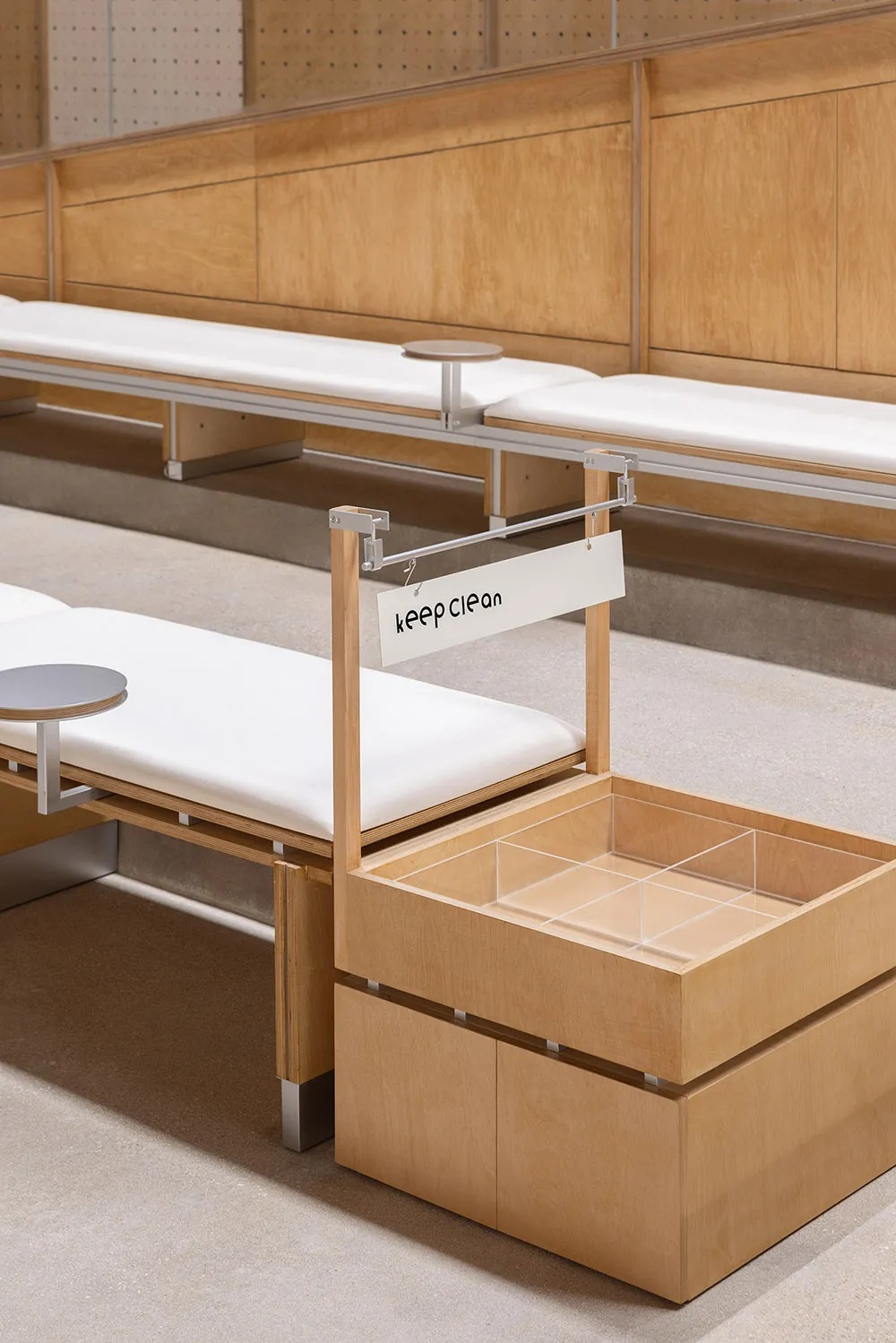 A modern minimalist bench with built-in storage unit made of light wood.