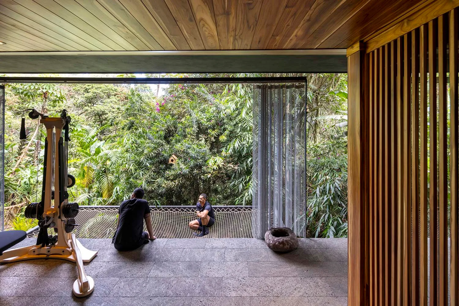 A minimalist residential space featuring wooden flooring and a workout machine with an outdoor view.