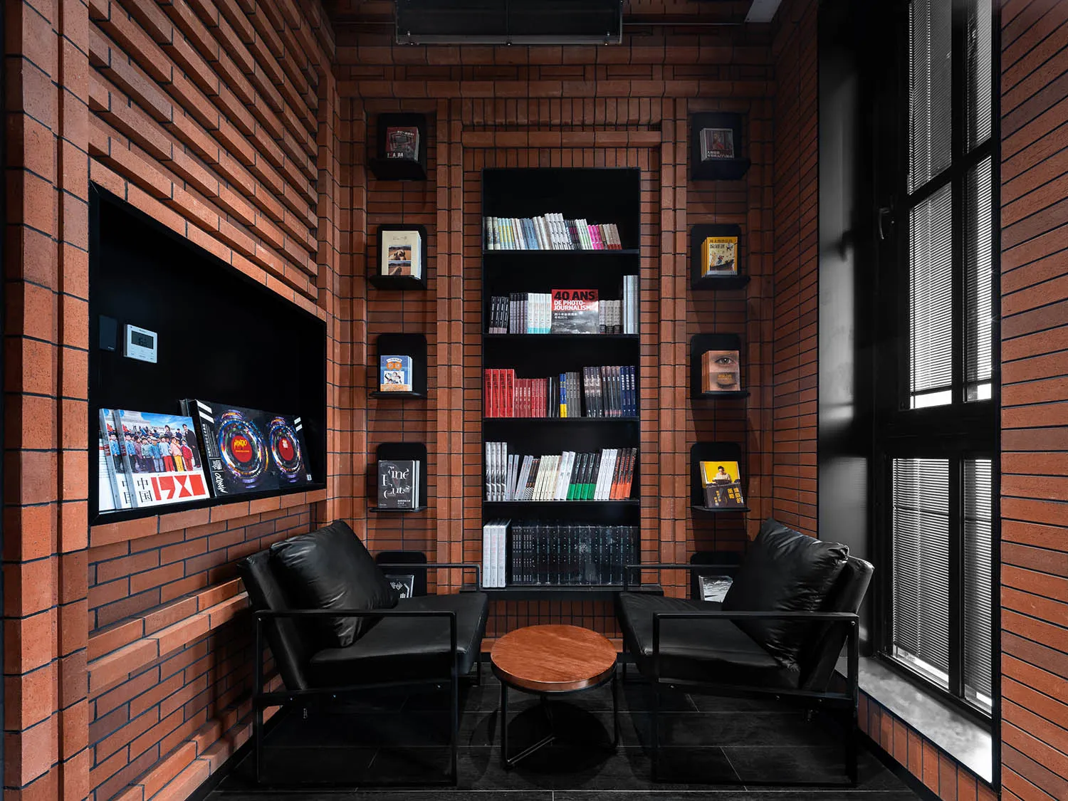 A cozy industrial-style lounge featuring a corner setup with black chairs and a wooden table, surrounded by brick walls and s