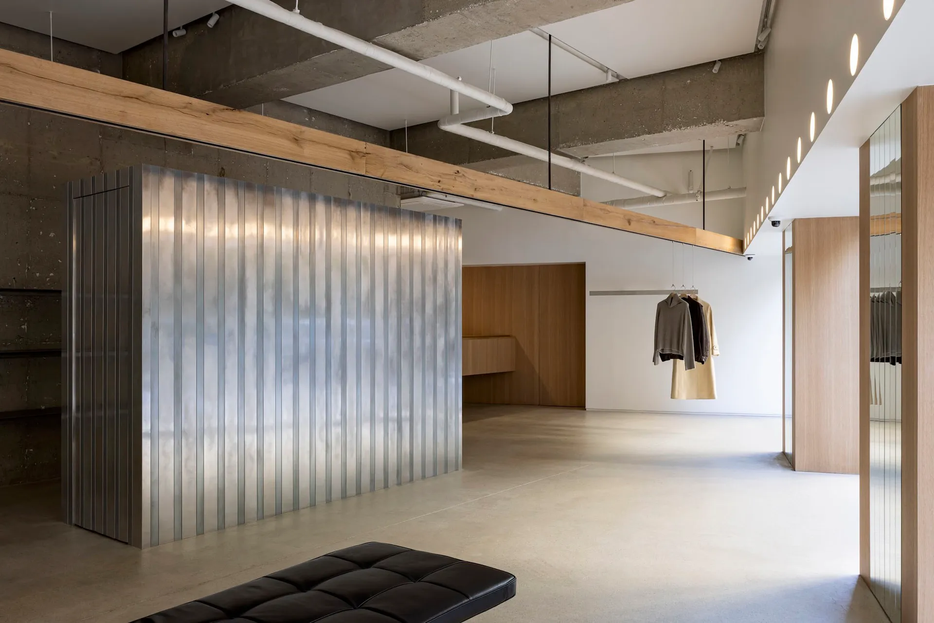 Modern minimalist clothing store with concrete, metal, and wooden elements.