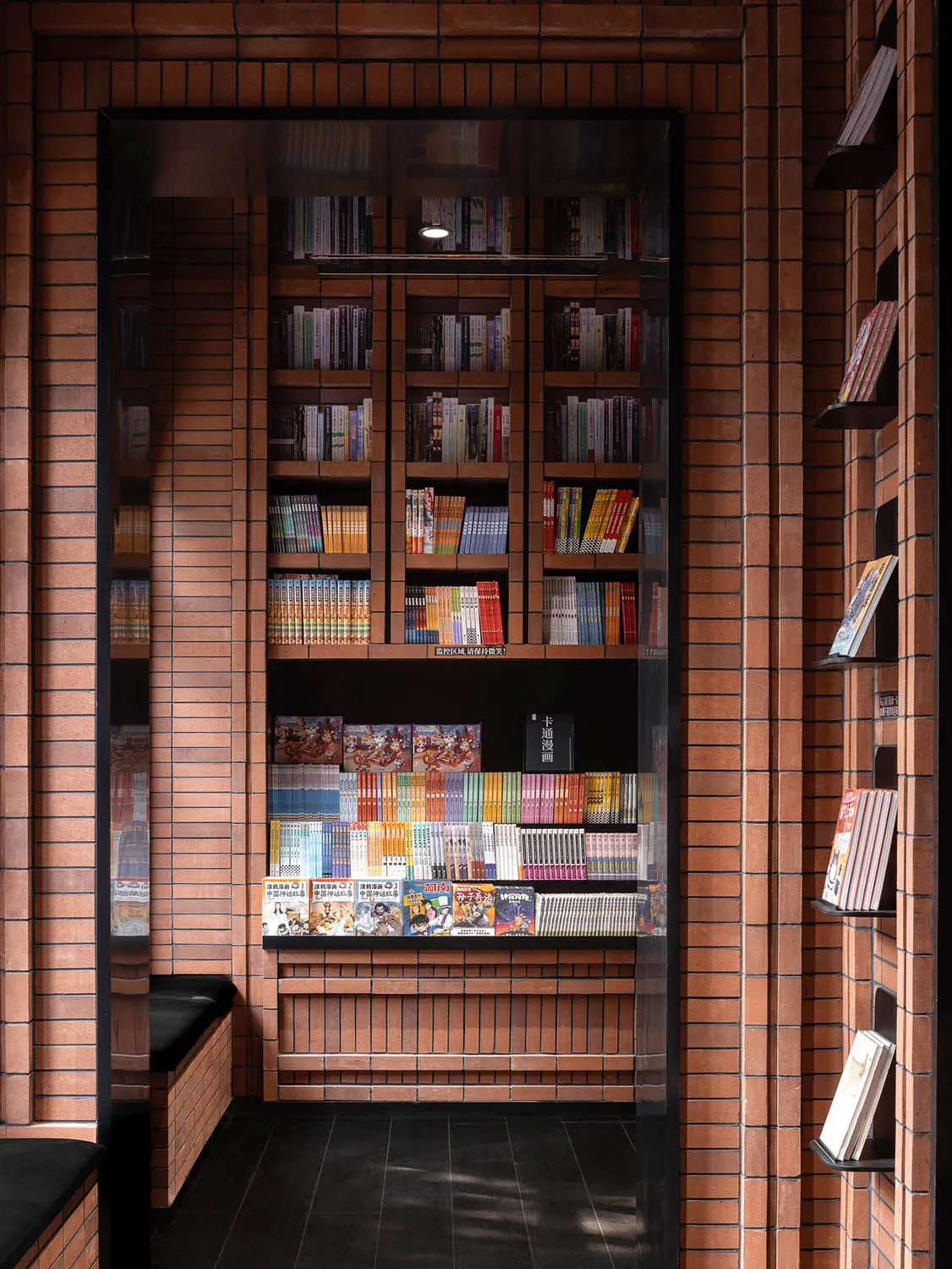 Modern library interior with brick walls, glass display cases, and numerous books on shelves.