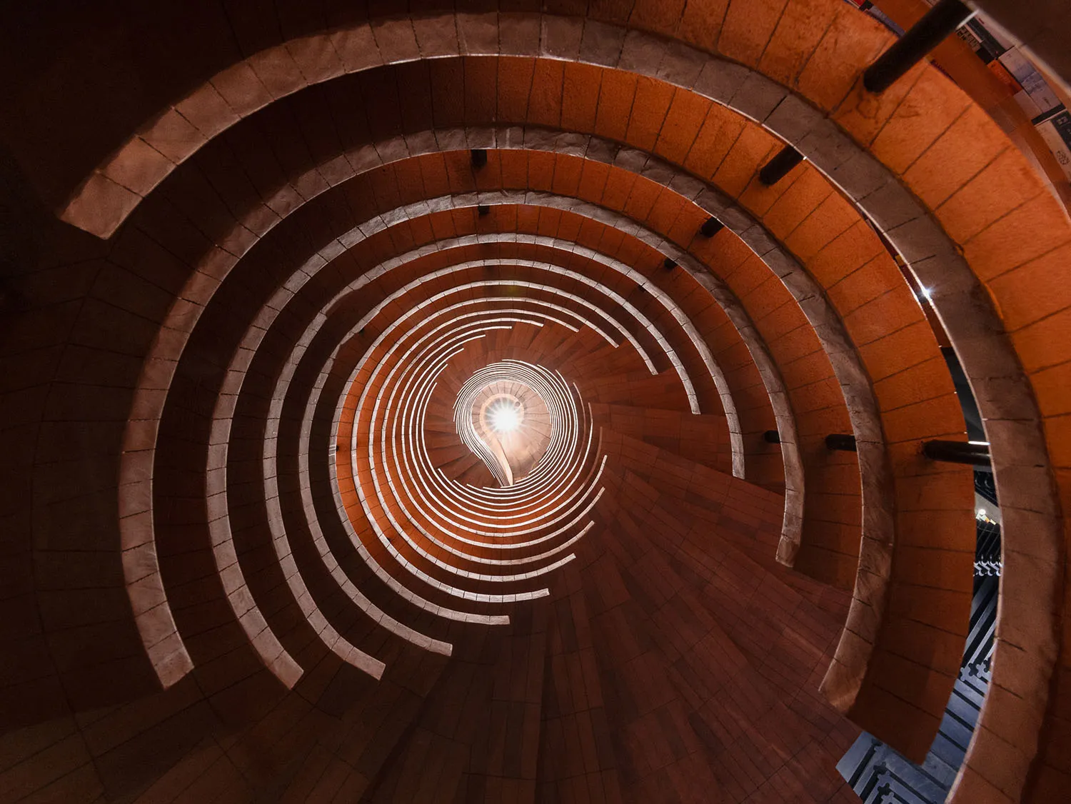 A spiral staircase made of brick, viewed from the bottom looking upwards.