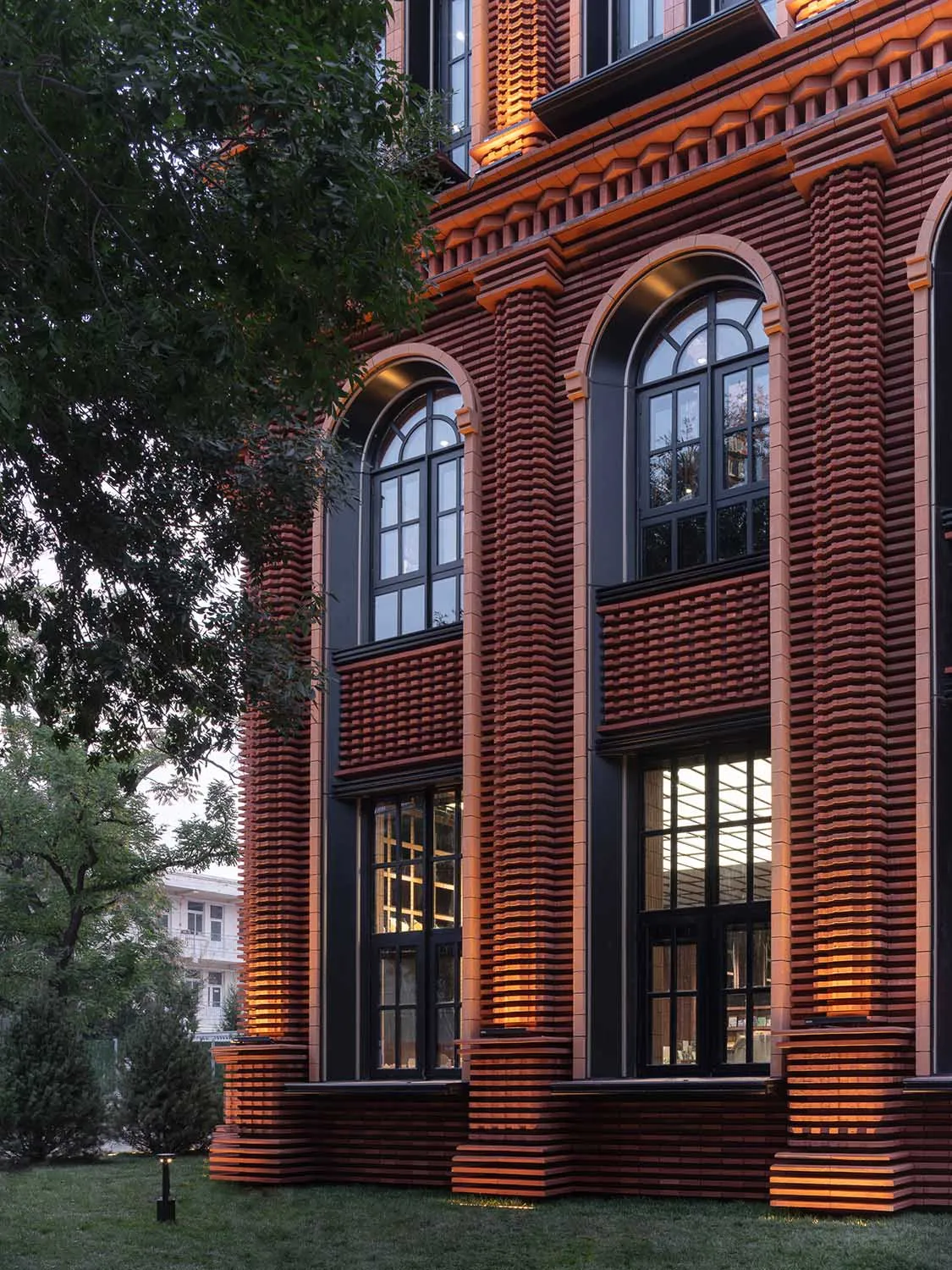 Modern building exterior featuring brick walls illuminated by warm lighting.