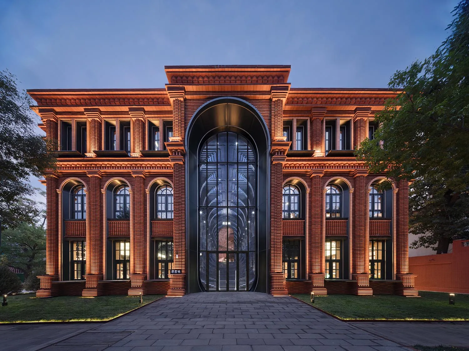 黃昏時分，一棟現代建築擁有磚造外牆與大型玻璃門。