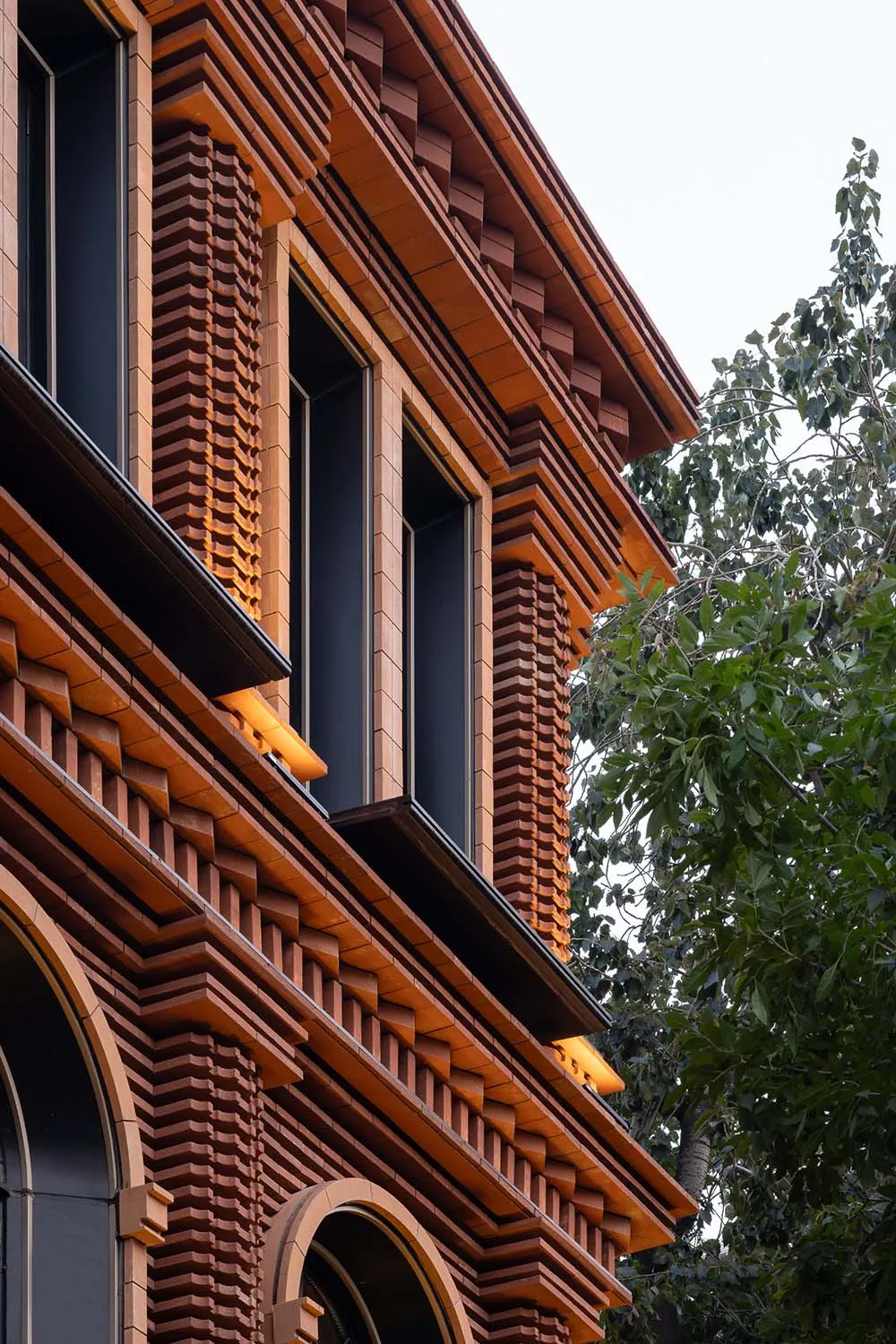 一座以磚材建構的現代建築外觀，搭配醒目的燈光設計。