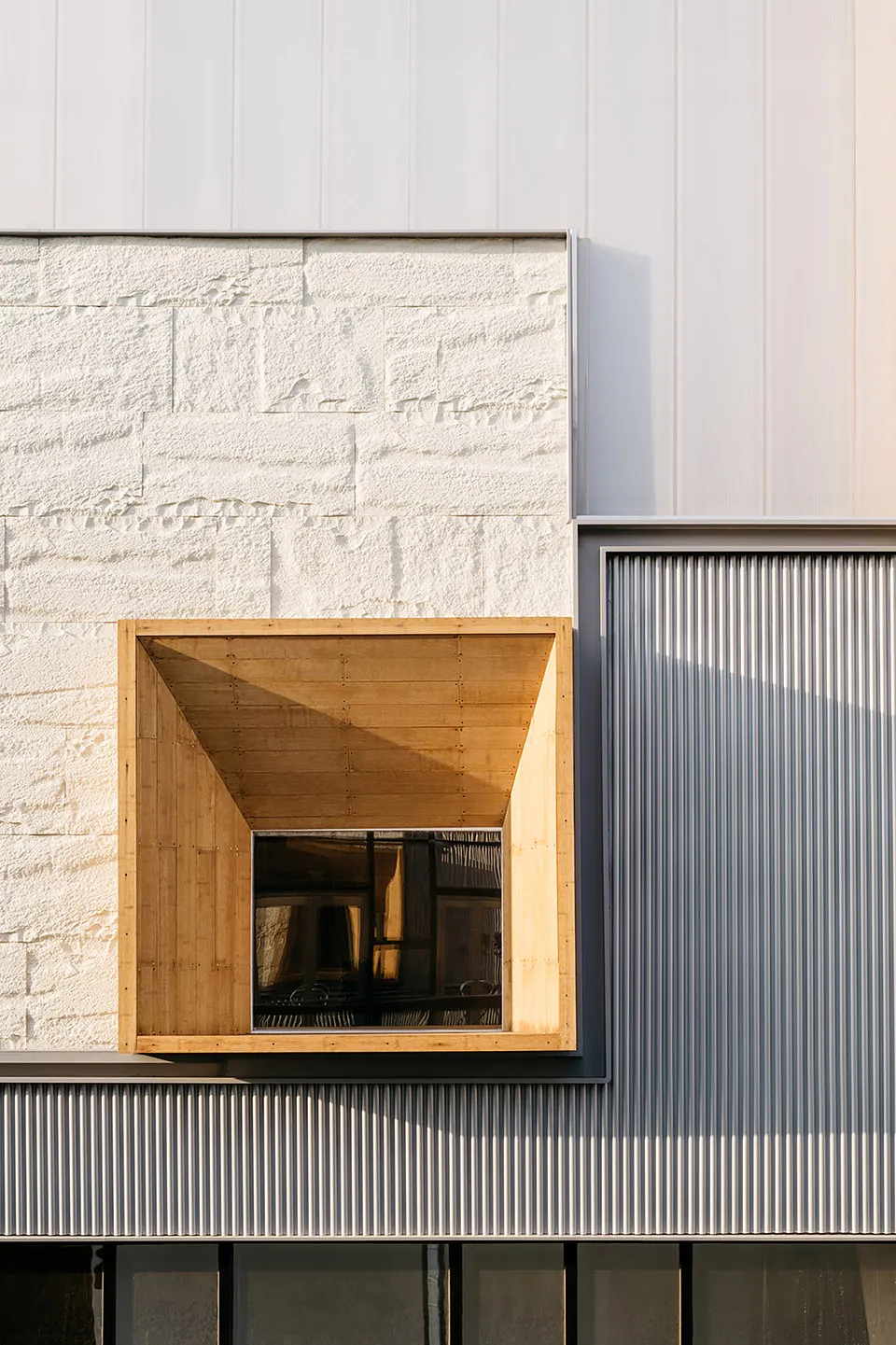 Modern architectural design featuring a wooden-framed window and an aluminum panel