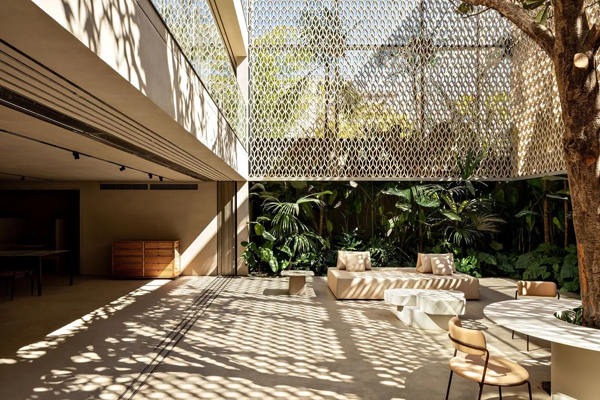 Modern minimalist living room with concrete flooring and a variety of green plants.