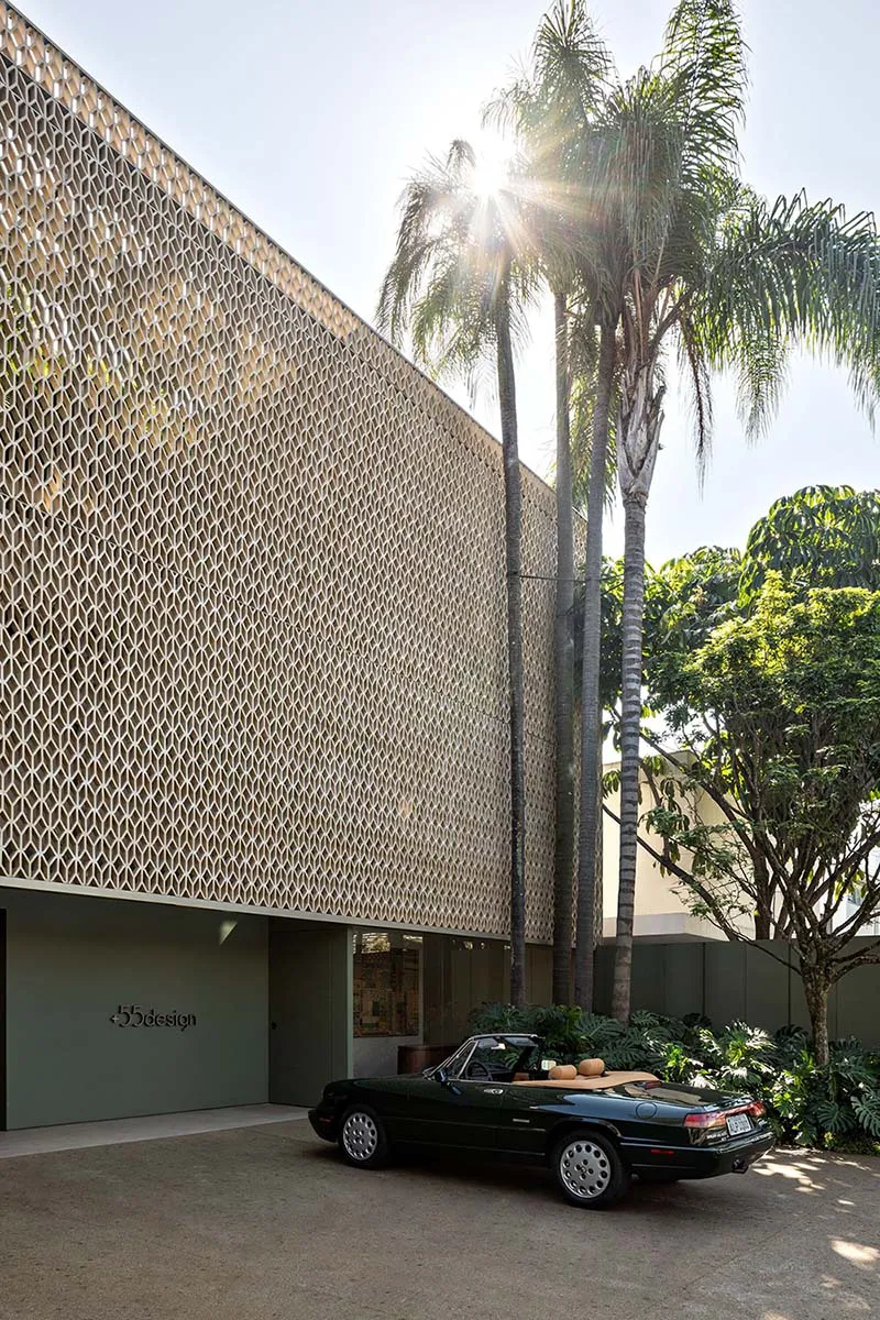 A modern exterior building with a patterned wooden facade and a classic black convertible car parked in front of it.