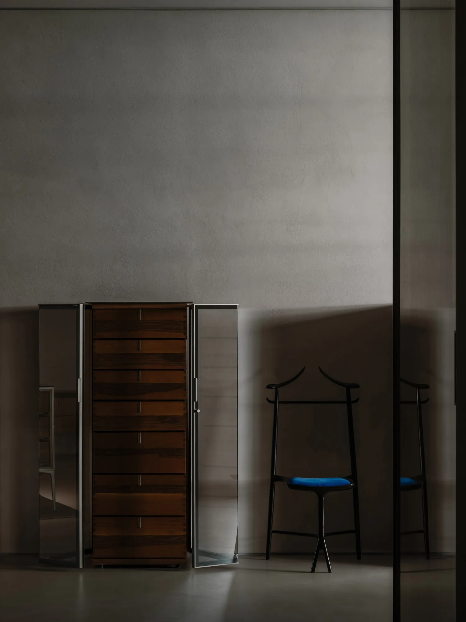 Modern interior design featuring a wooden wardrobe and a black valet stand with blue cushion.