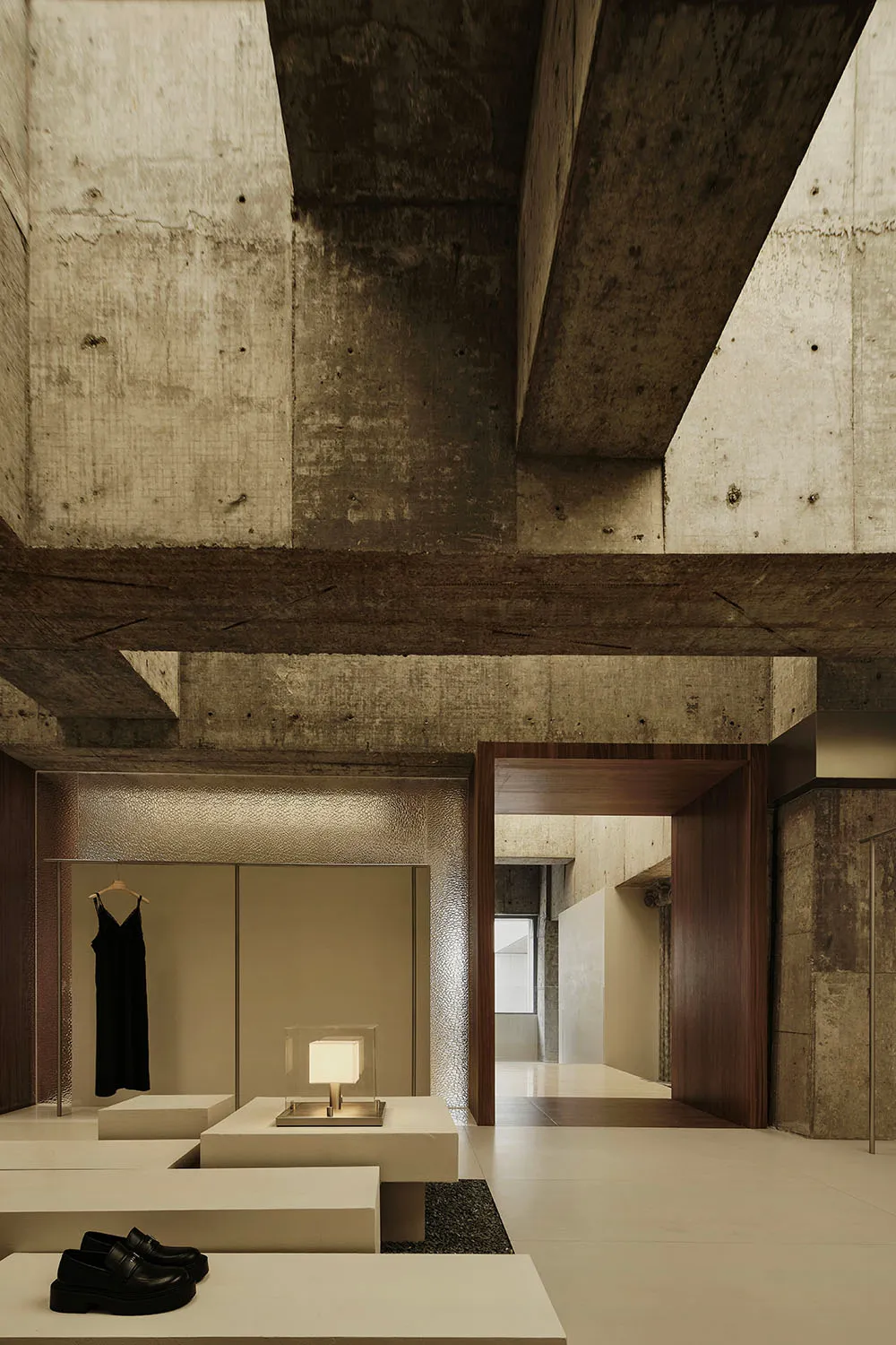 Minimalist retail store entrance with concrete walls and ceiling beams