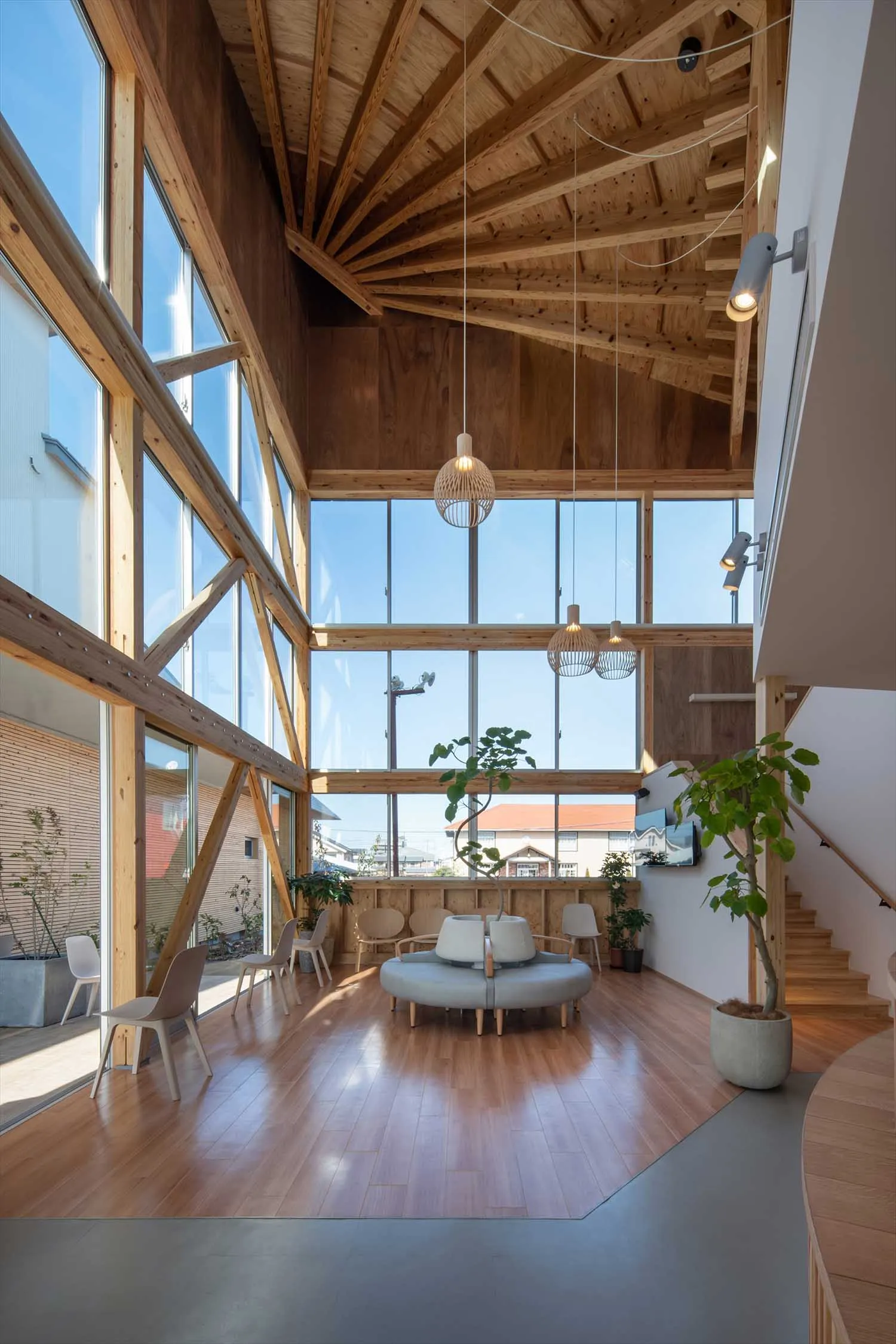A modern living room with wooden walls and ceiling beams, featuring a circular sofa and white chairs.