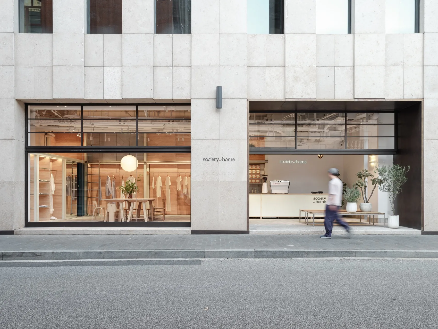 Modern retail storefront with concrete and glass materials, featuring clothing display.