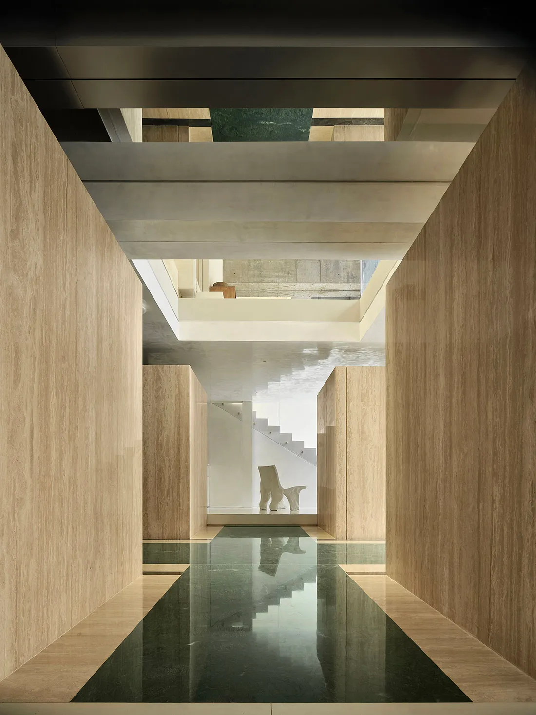 A modern interior space featuring concrete walls, natural light, and a minimalist design with a sleek, black floor.