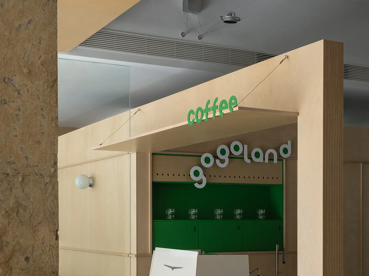 Modern coffee shop interior featuring wooden paneling and green accents.