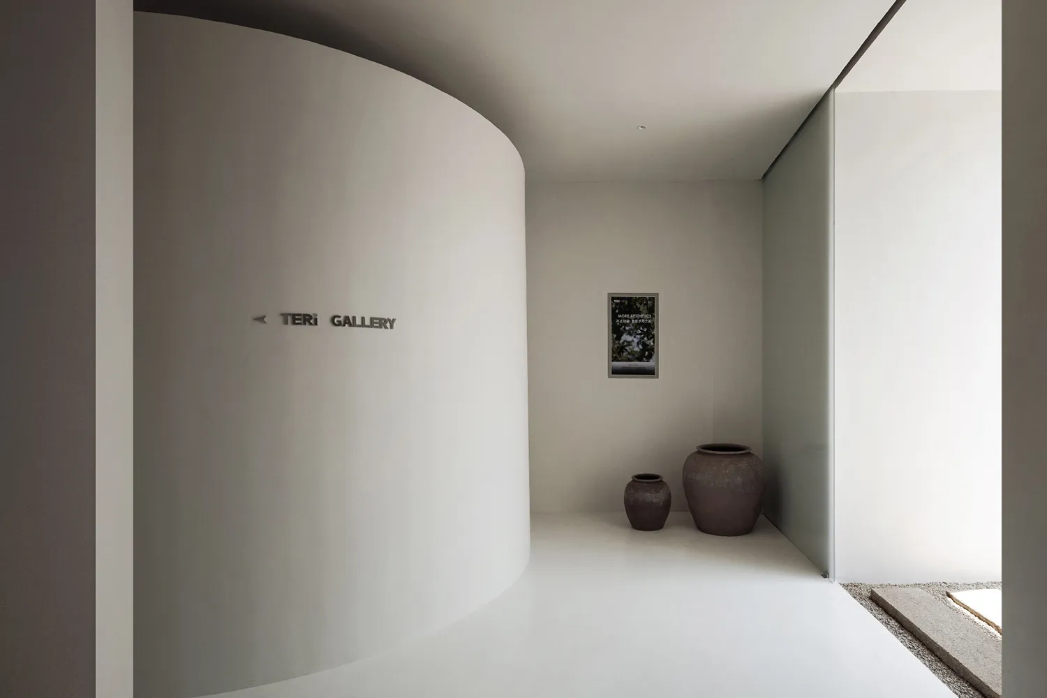A minimalist white interior space with concrete walls and two vases on the floor.