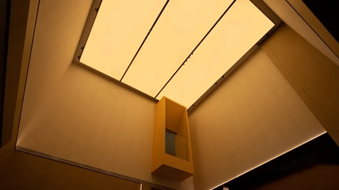 A modern corridor with a floating lightbox on the ceiling.