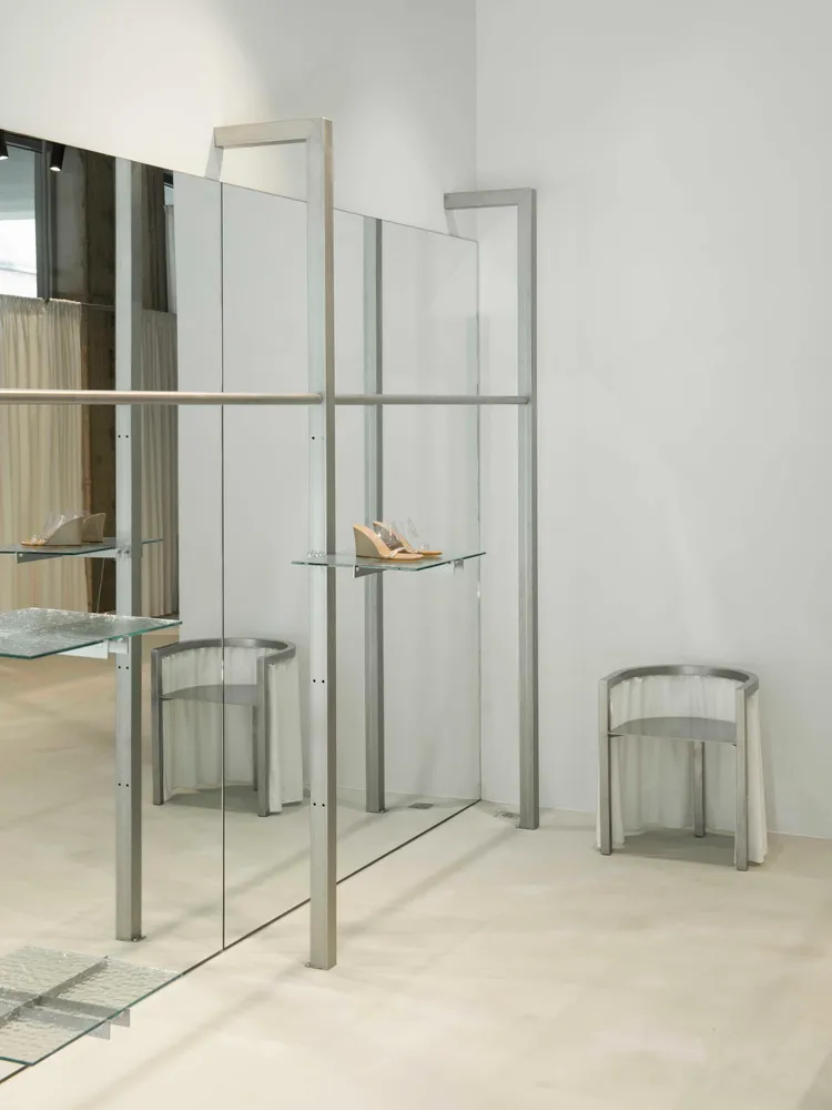 Modern retail display area featuring glass and metal shelving and seating arrangements.