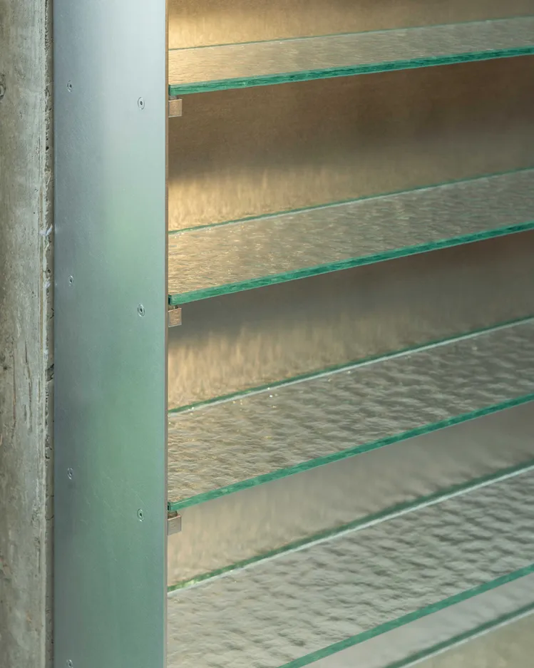 Modern interior design featuring glass and metal shelves with textured glass panels.