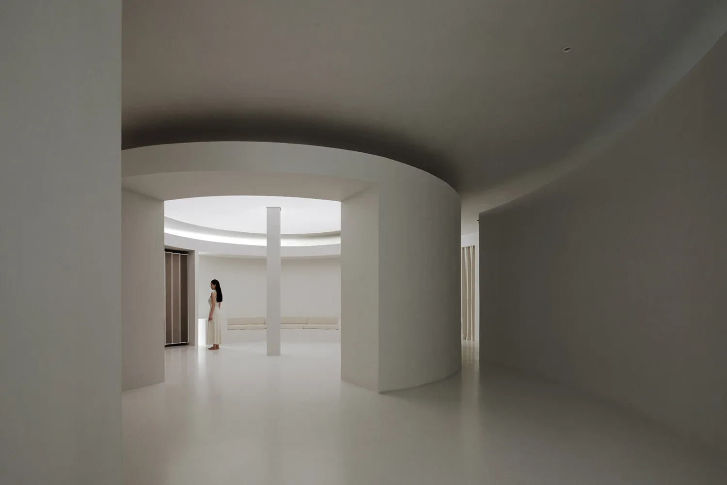 Modern minimalist interior space with white materials and curved architecture.