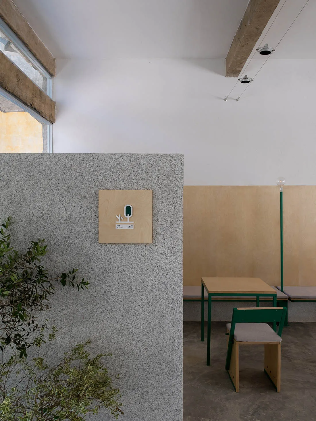 簡約餐廳室內空間,特色為帶有綠色點綴的質感混凝土吧台。