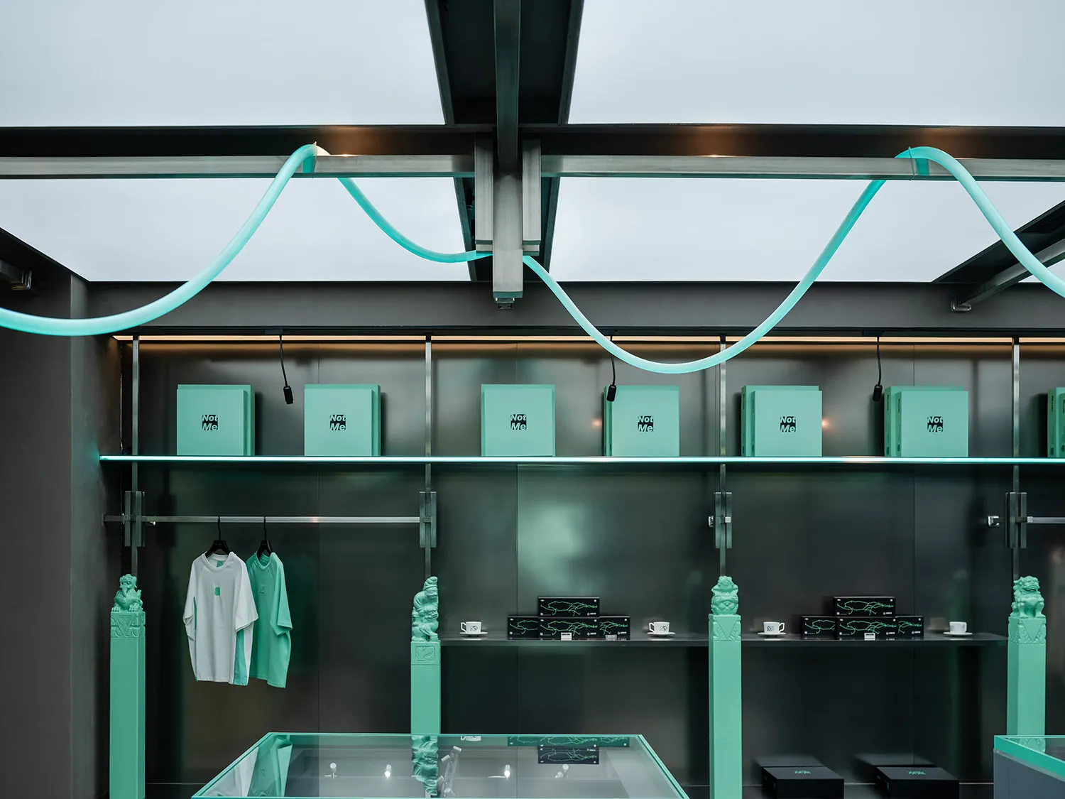 A modern storefront with green lighting and mixed materials, featuring shelves with boxes and clothing items.