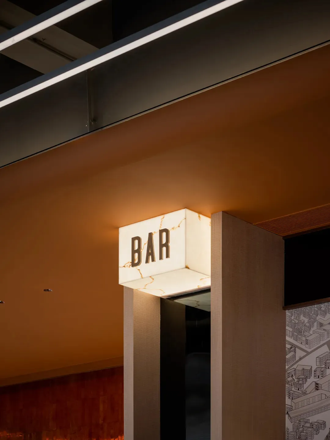 在極簡工業風室內空間中,一塊金屬材質的照明招牌顯示著「BAR」字樣。