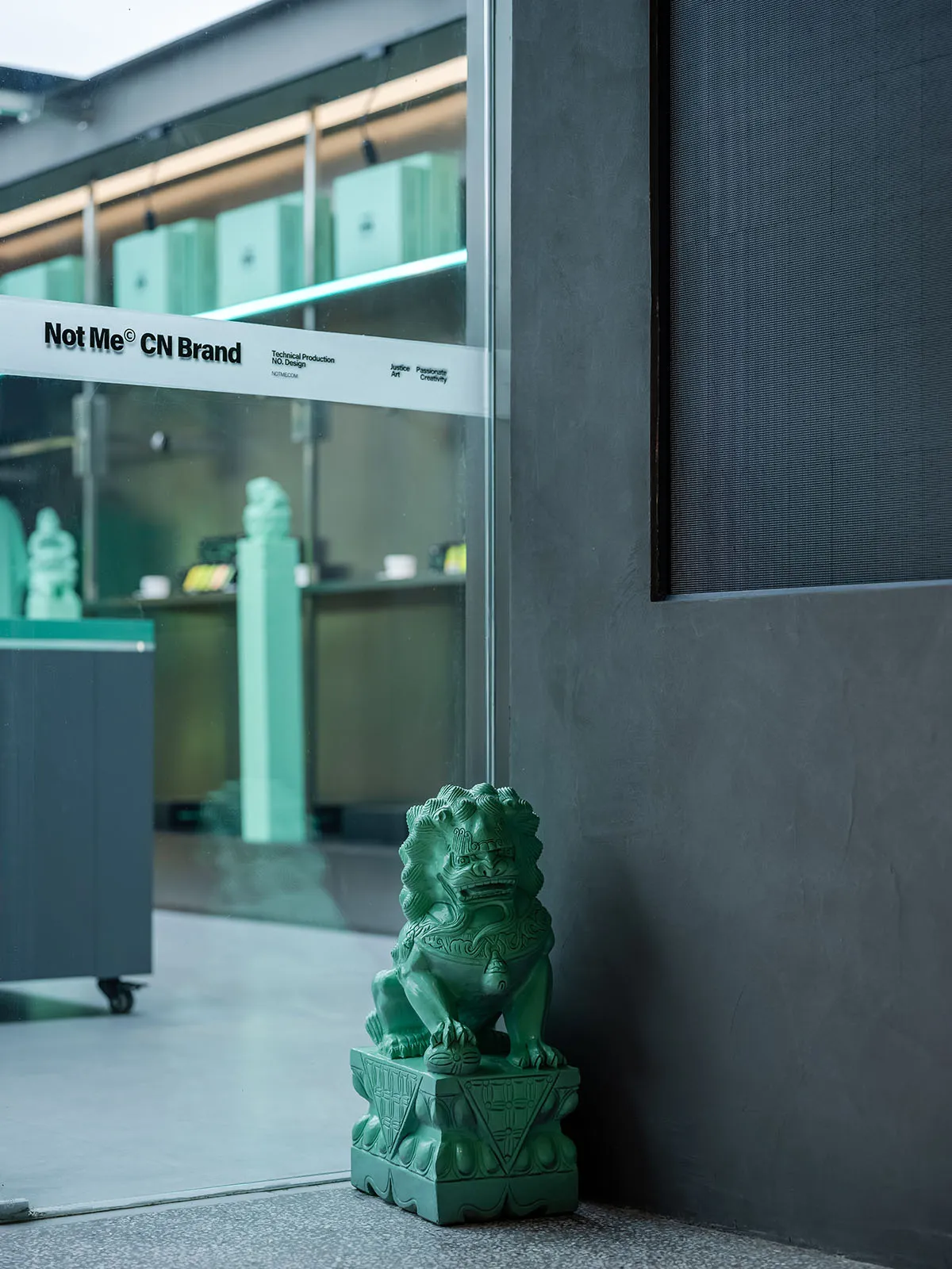 A green ceramic statue sitting on a pedestal in a shopping mall storefront display.