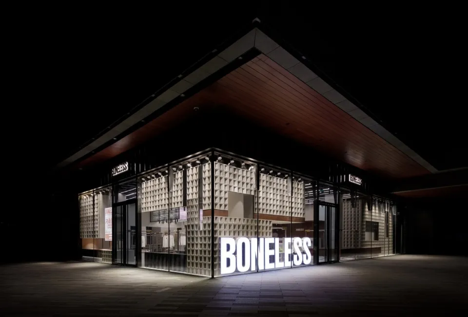 A modern retail storefront with glass walls, wooden elements, and black lighting.