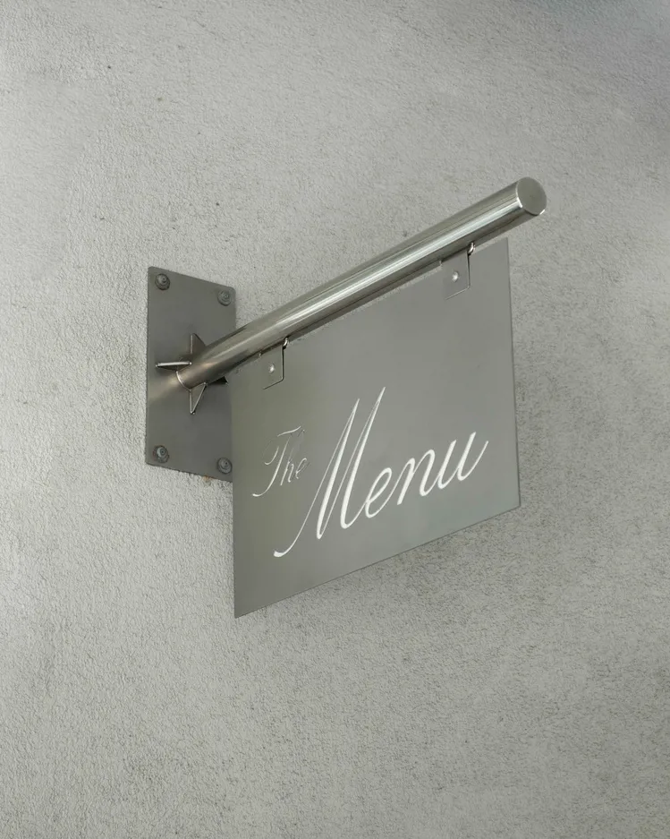 A metal menu sign hanging on a wall.