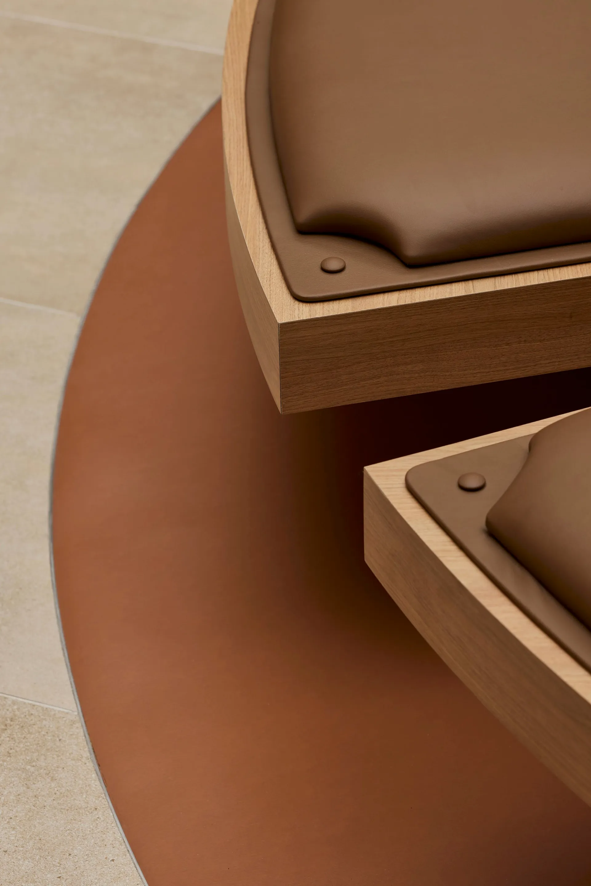 Close-up of a modern interior design featuring a wooden furniture piece with leather accents and metal rivets.