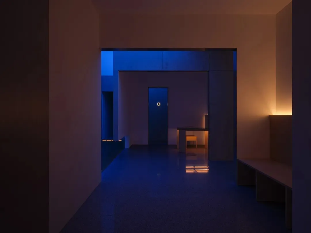 A minimalist interior with terrazzo flooring and wooden furniture, featuring a closed door.