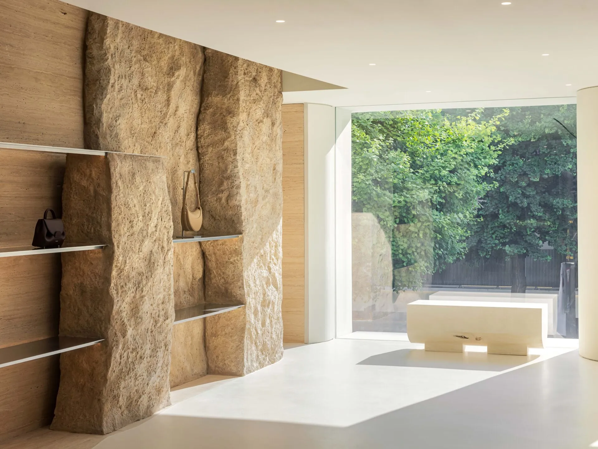 Minimalist retail store featuring stone walls and a large glass window.