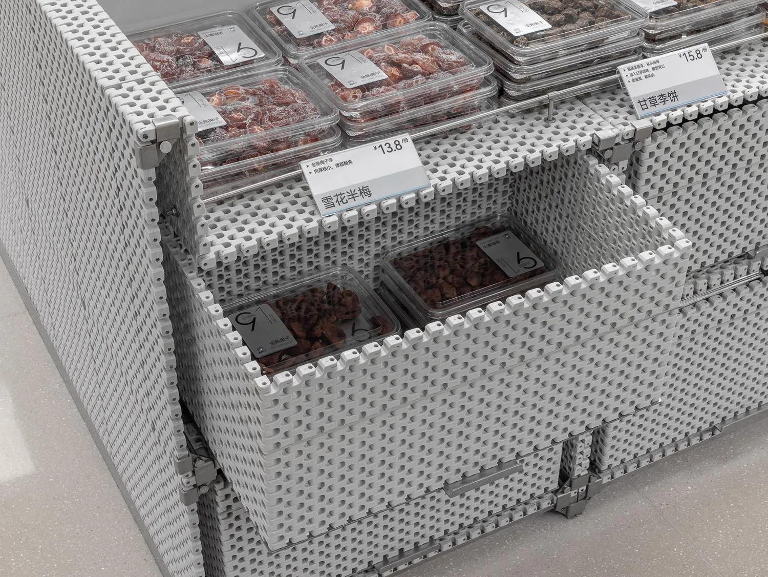 A display case showcasing dried fruits in plastic containers with price tags.
