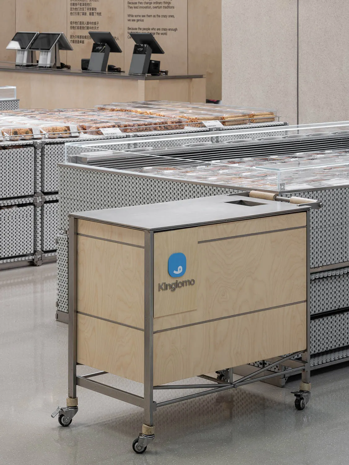 A wooden supermarket food counter cart with metal wheels and a glass shelf.