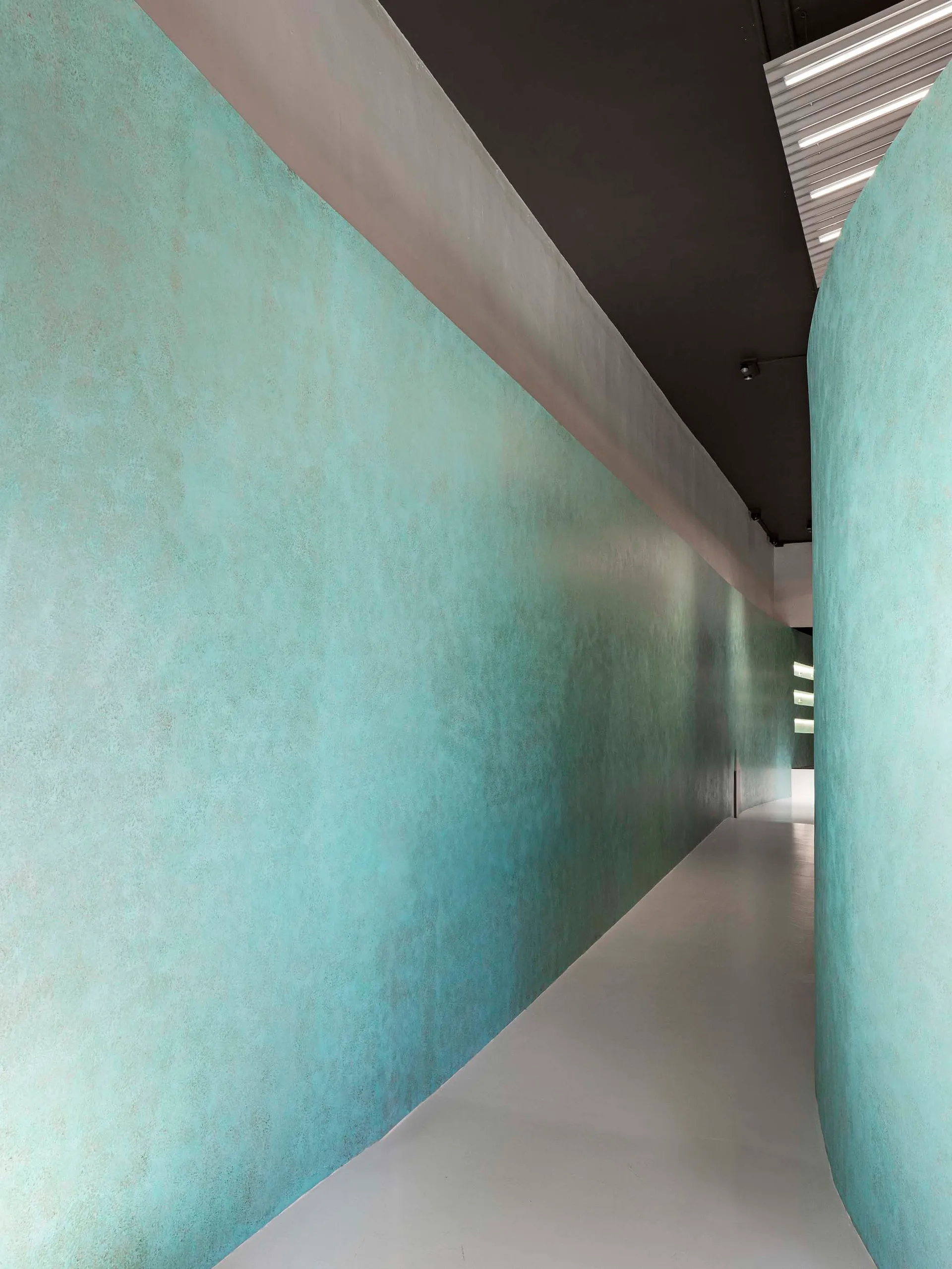 Modern interior corridor with concrete walls and illuminated lighting fixtures.