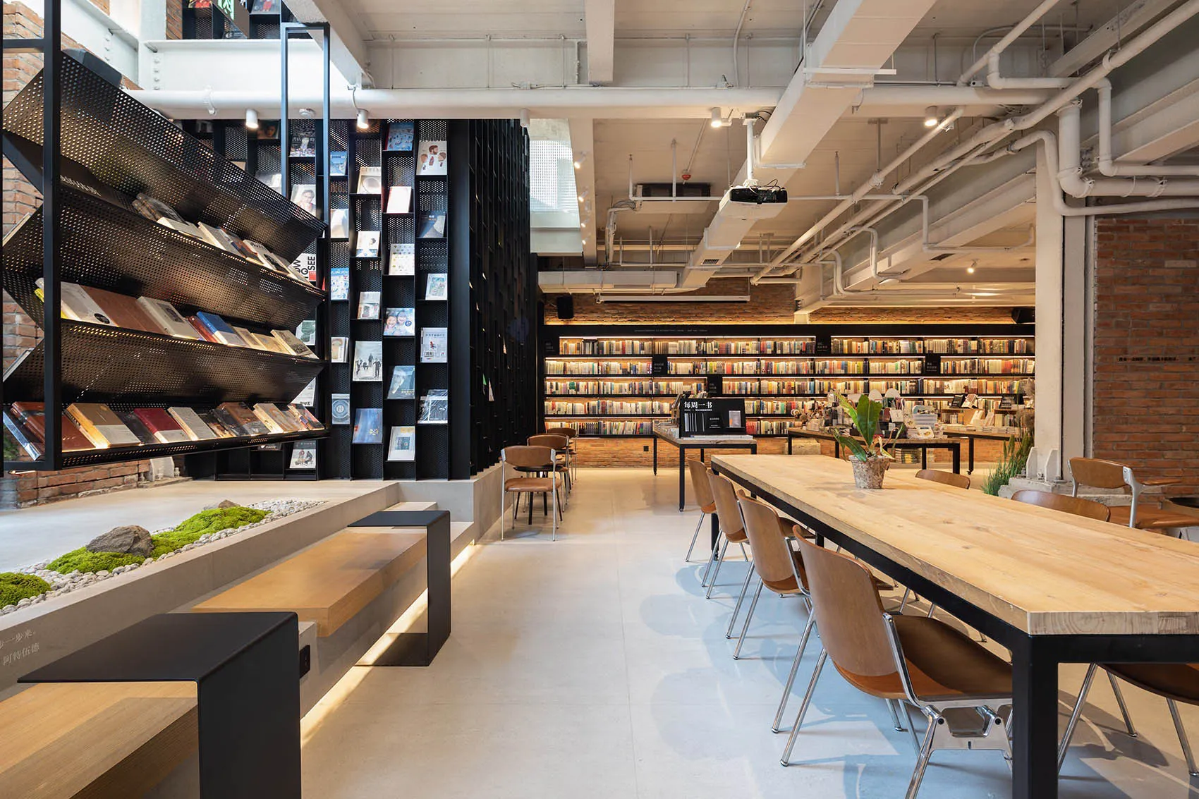 A modern industrial-style library with exposed brick walls, concrete flooring, and metal shelving.