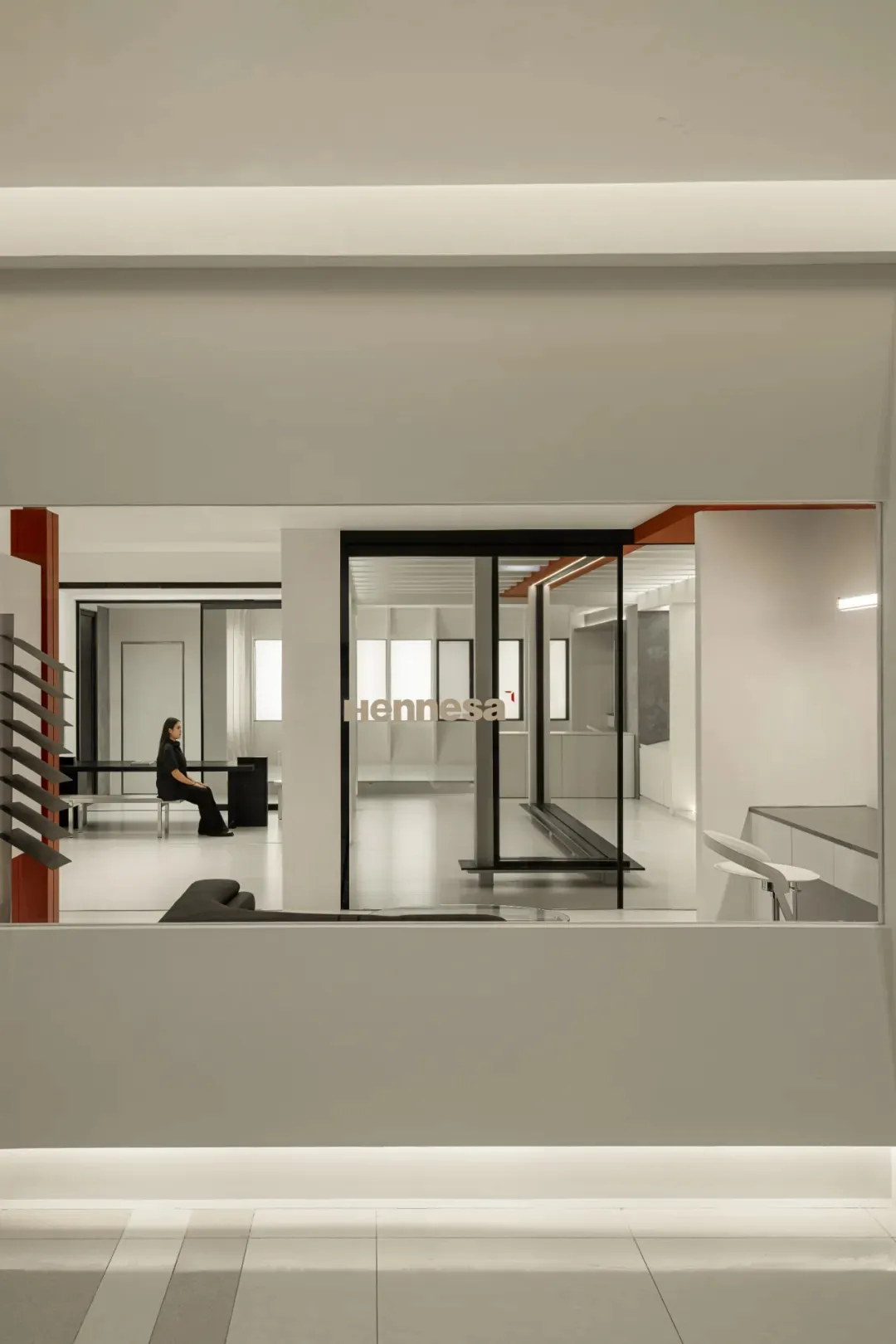 A modern office space with transparent glass walls and floor-to-ceiling windows.