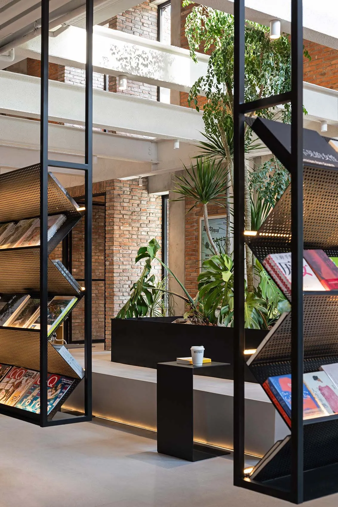 A modern industrial library interior with exposed concrete walls and metal shelves, featuring green plants for decoration.