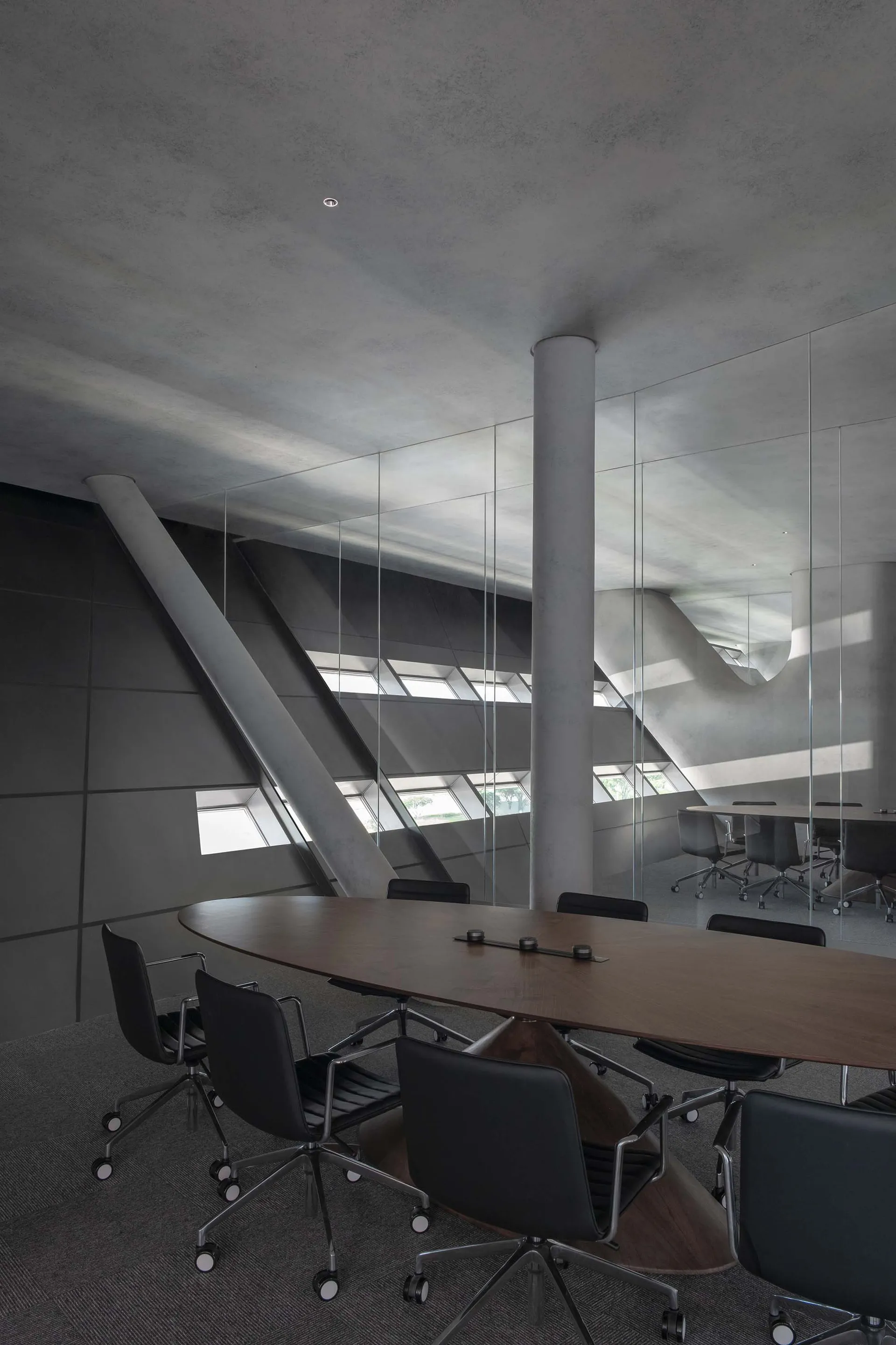 Modern conference room with glass walls and concrete floor.