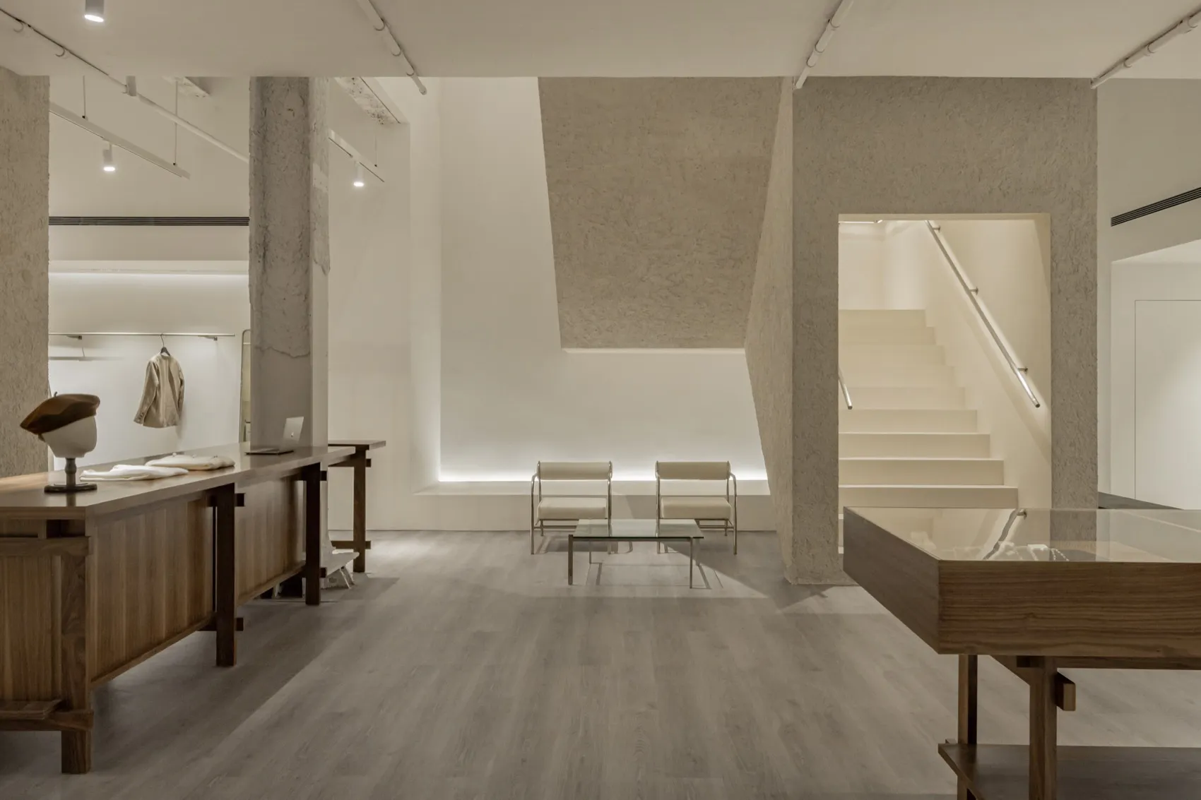 View of a minimalist retail space featuring concrete walls and wooden furniture.
