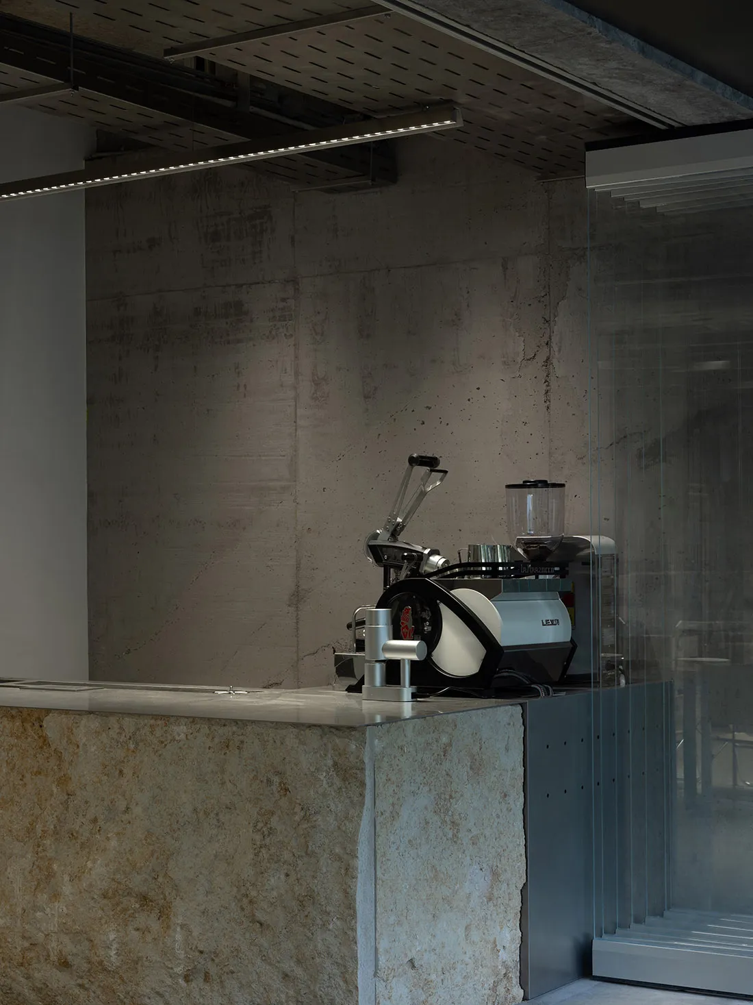 Modern coffee shop interior with a concrete counter and industrial coffee machine.