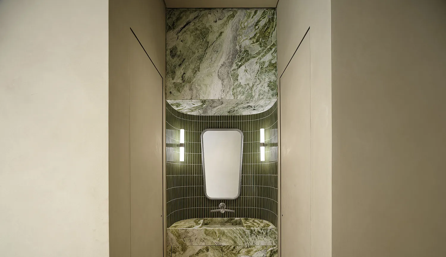 A sleek, modern bathroom with green marble tile and a mirror above a sink.