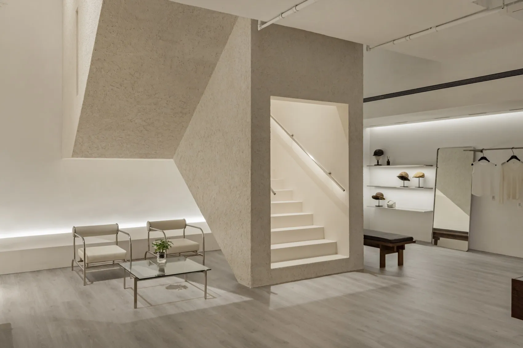 Modern minimalist interior with concrete elements, featuring a geometric staircase and a minimalistic seating area with chair