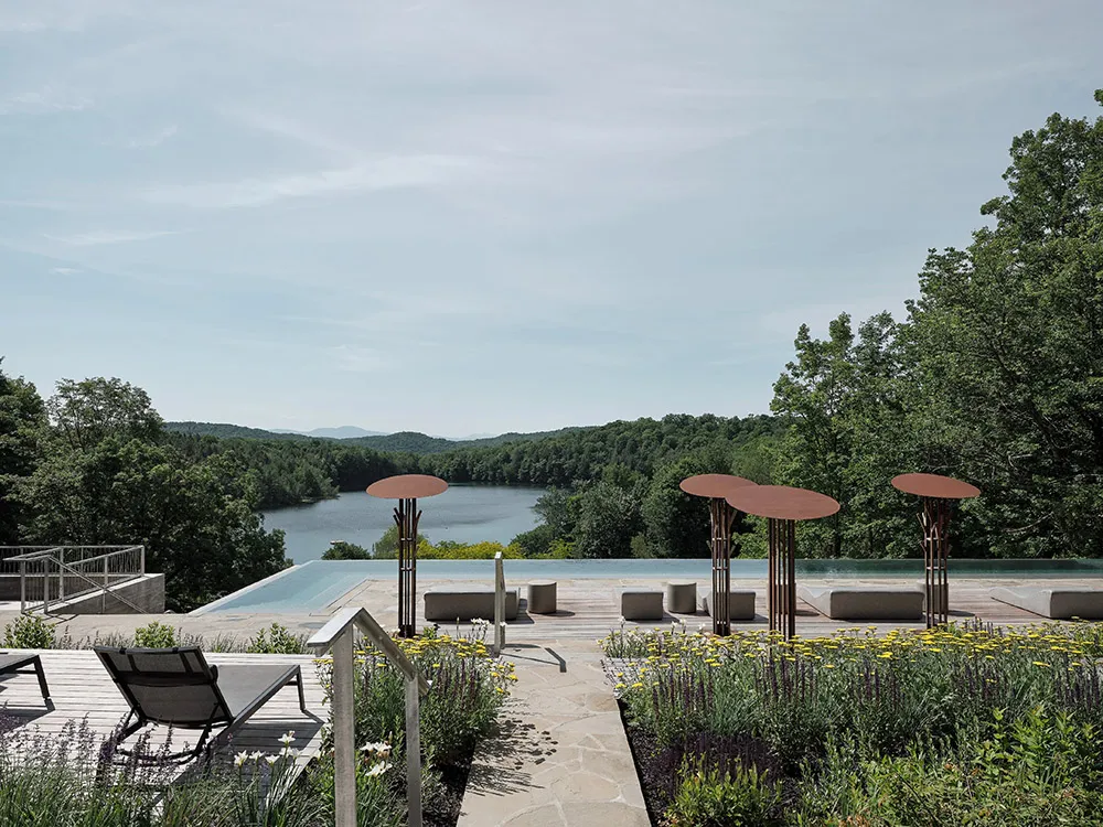 Concrete flooring in a modern residential house with a pool and view of a serene lake surrounded by nature.