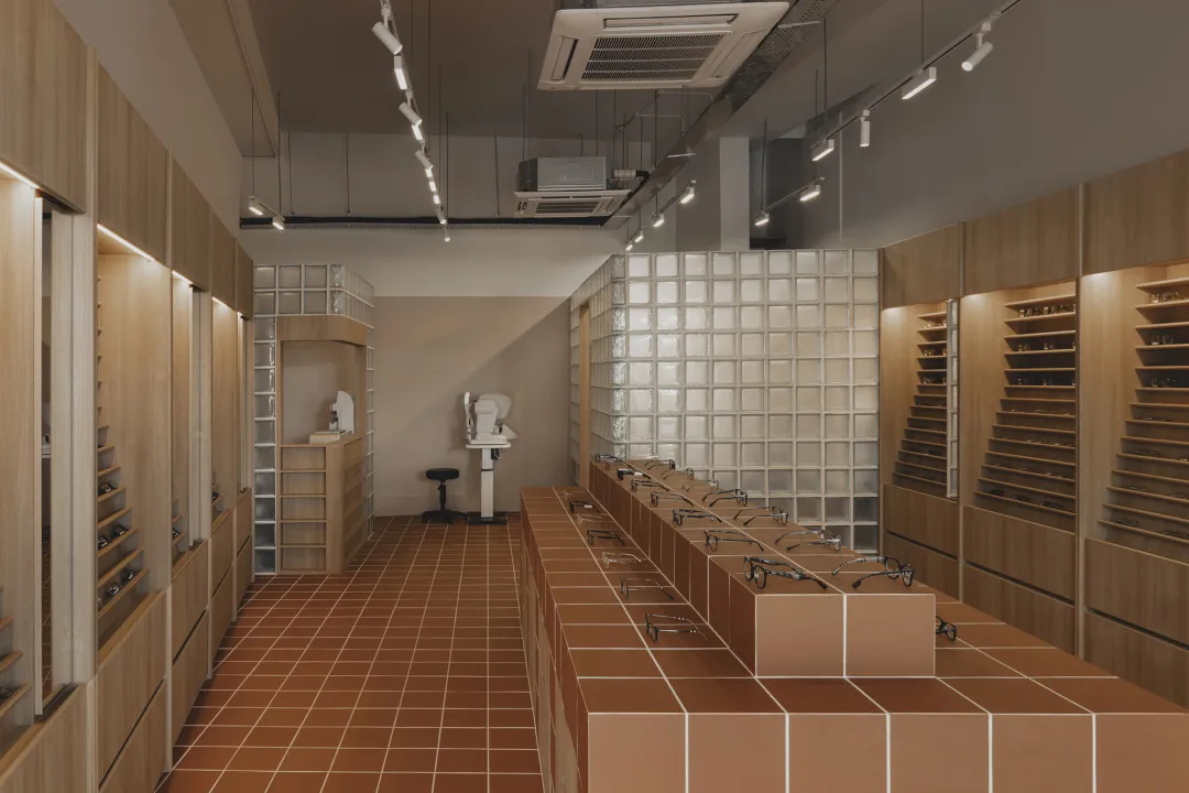 Modern interior of an optical shop with wooden finishes and display shelves showcasing glasses.