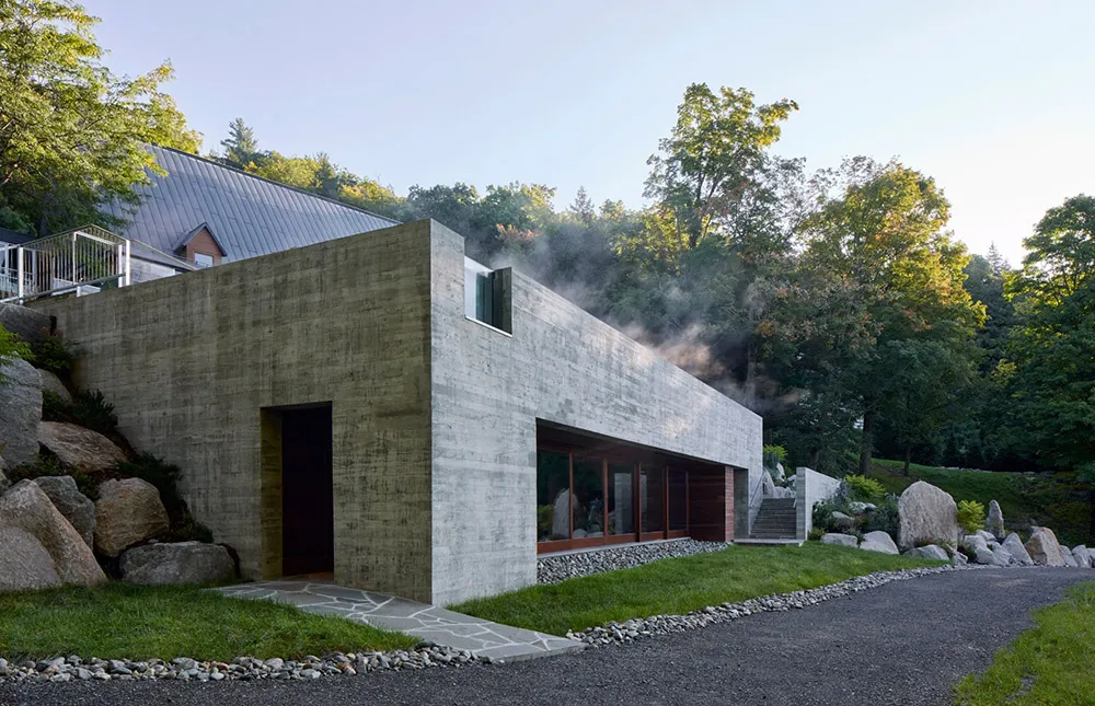 Modern residential home with concrete walls and a glass window on a hillside.