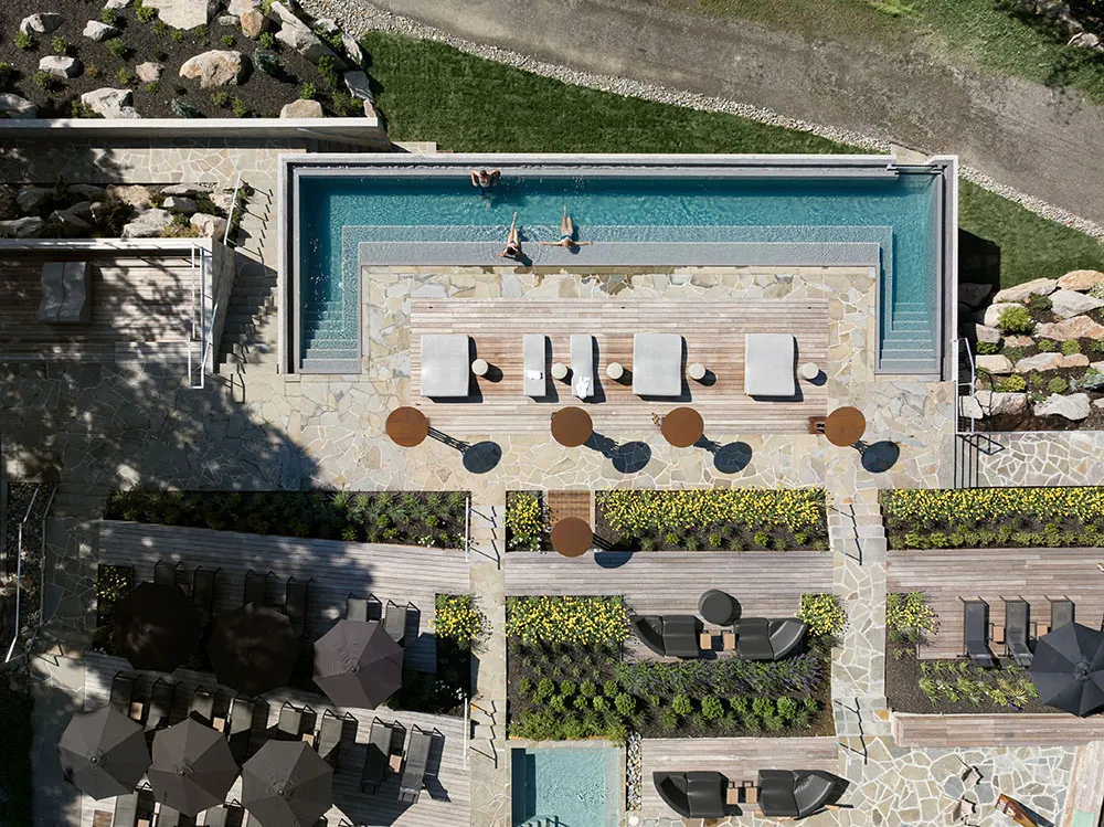 A modern outdoor space with stone pool, lounge chairs, and landscaping