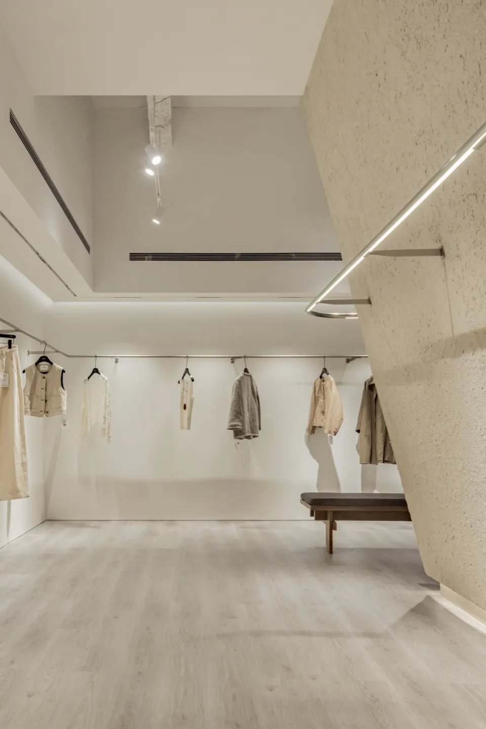 現代零售店室內空間,採用極簡設計、中性色調材料,並陳列服裝。
